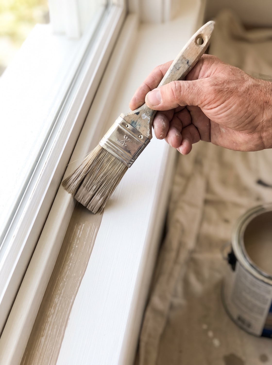 A painter cutting a clean line along trim with a brush