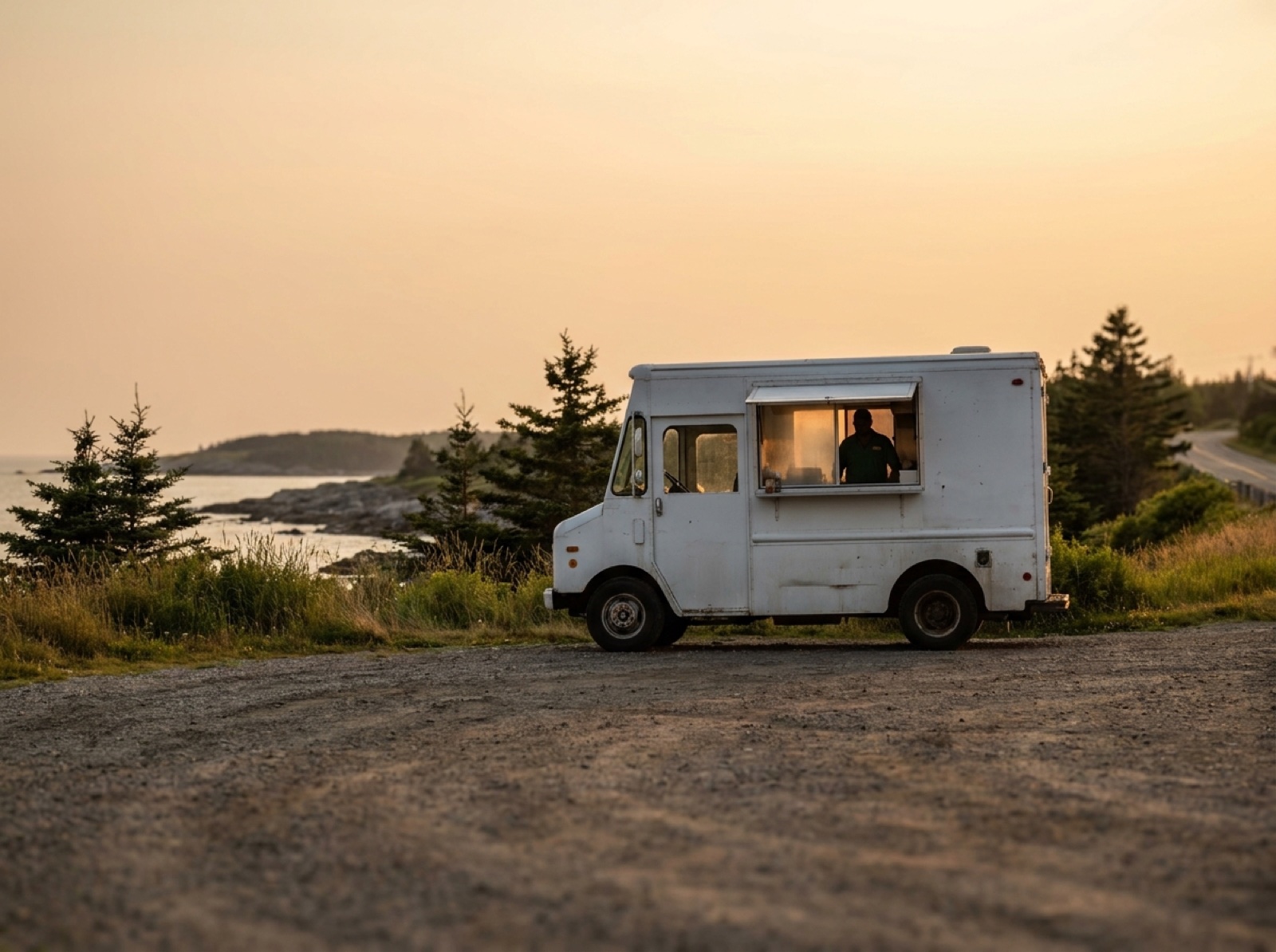 Curbside Eats food truck parked on a rural Nova Scotia roadside at golden hour with the serving window lit