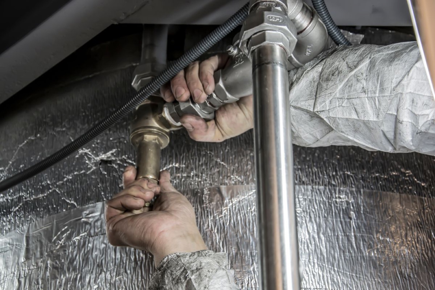 A plumber connecting pipe fittings under a sink
